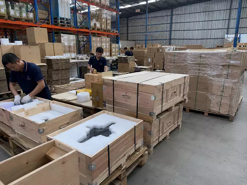Workers packing wooden boxes with fitted foam inserts in an export packing area